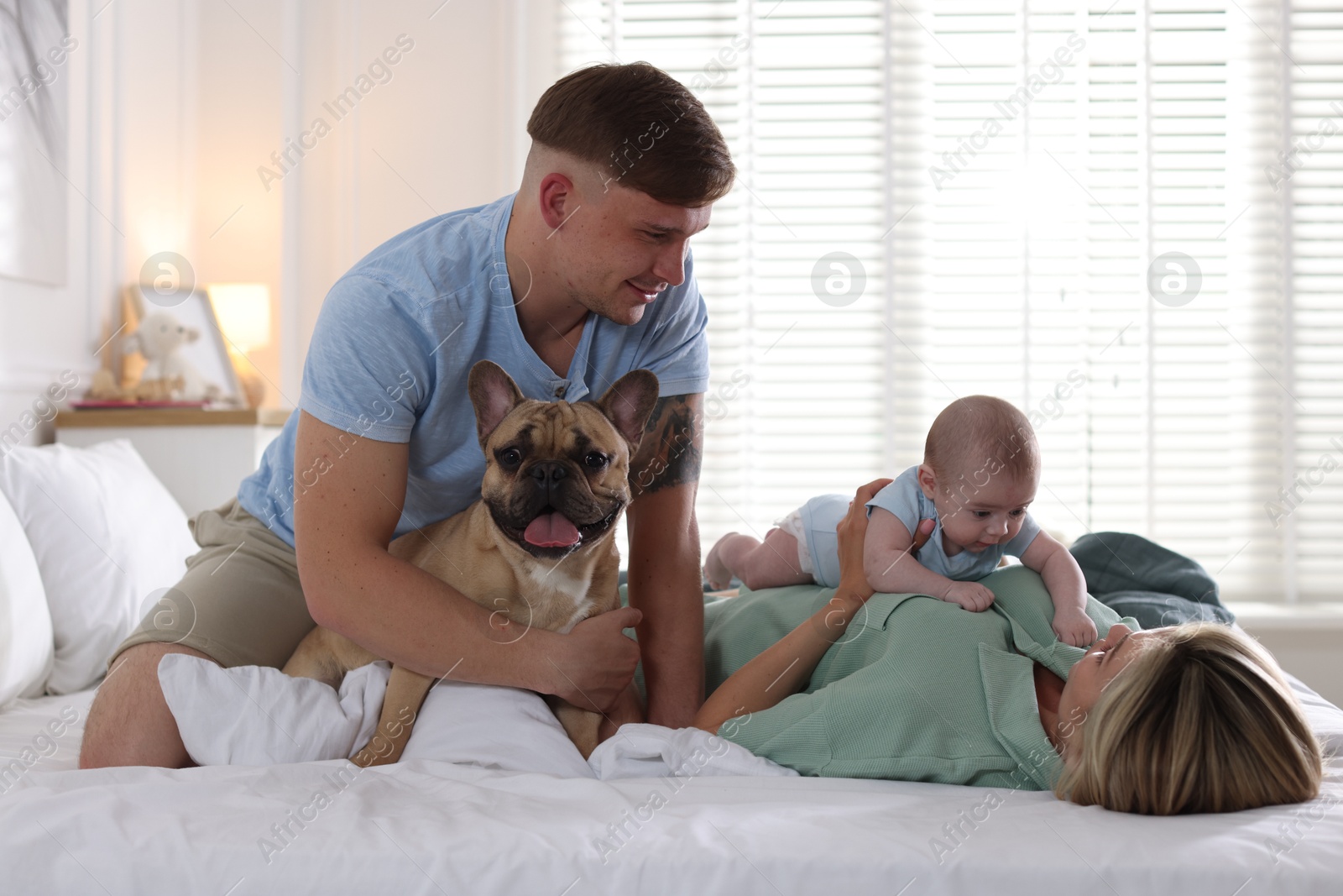 Happy family with little baby and cute dog on bed at home Photo of Happy family with little baby and cute dog on bed at home