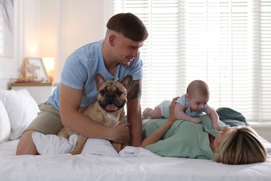 Photo of Happy family with little baby and cute dog on bed at home