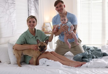 Photo of Happy family with little baby and cute dog on bed at home