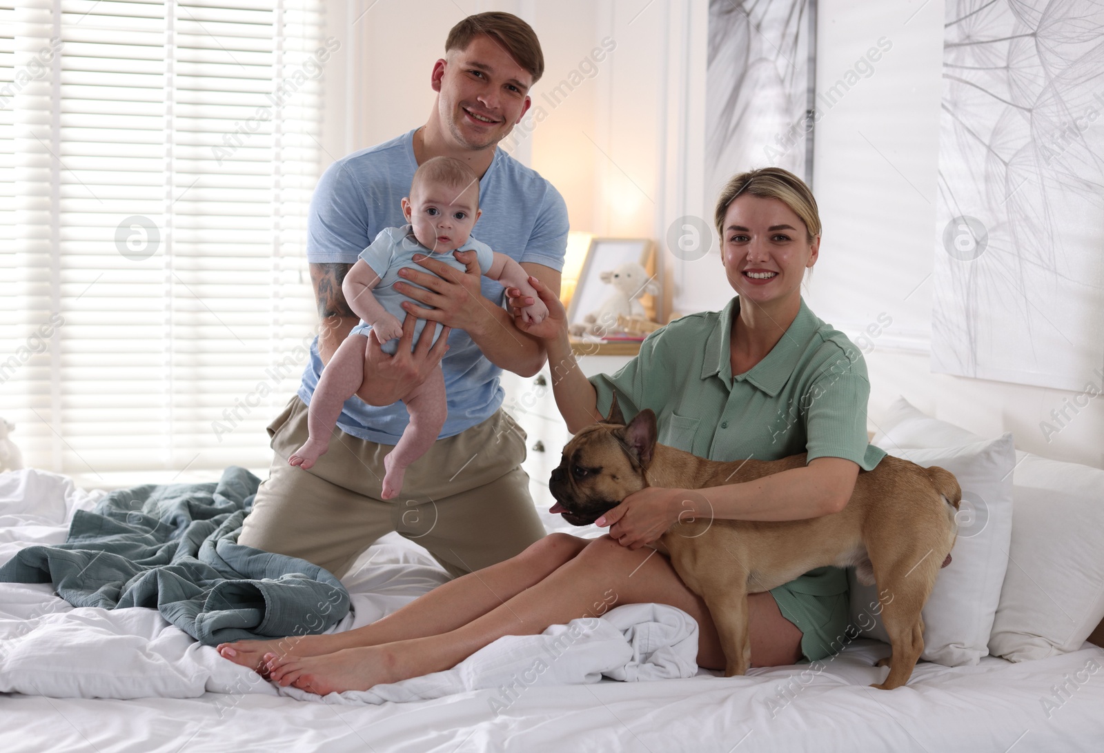 Happy family with little baby and cute dog on bed at home Photo of Happy family with little baby and cute dog on bed at home