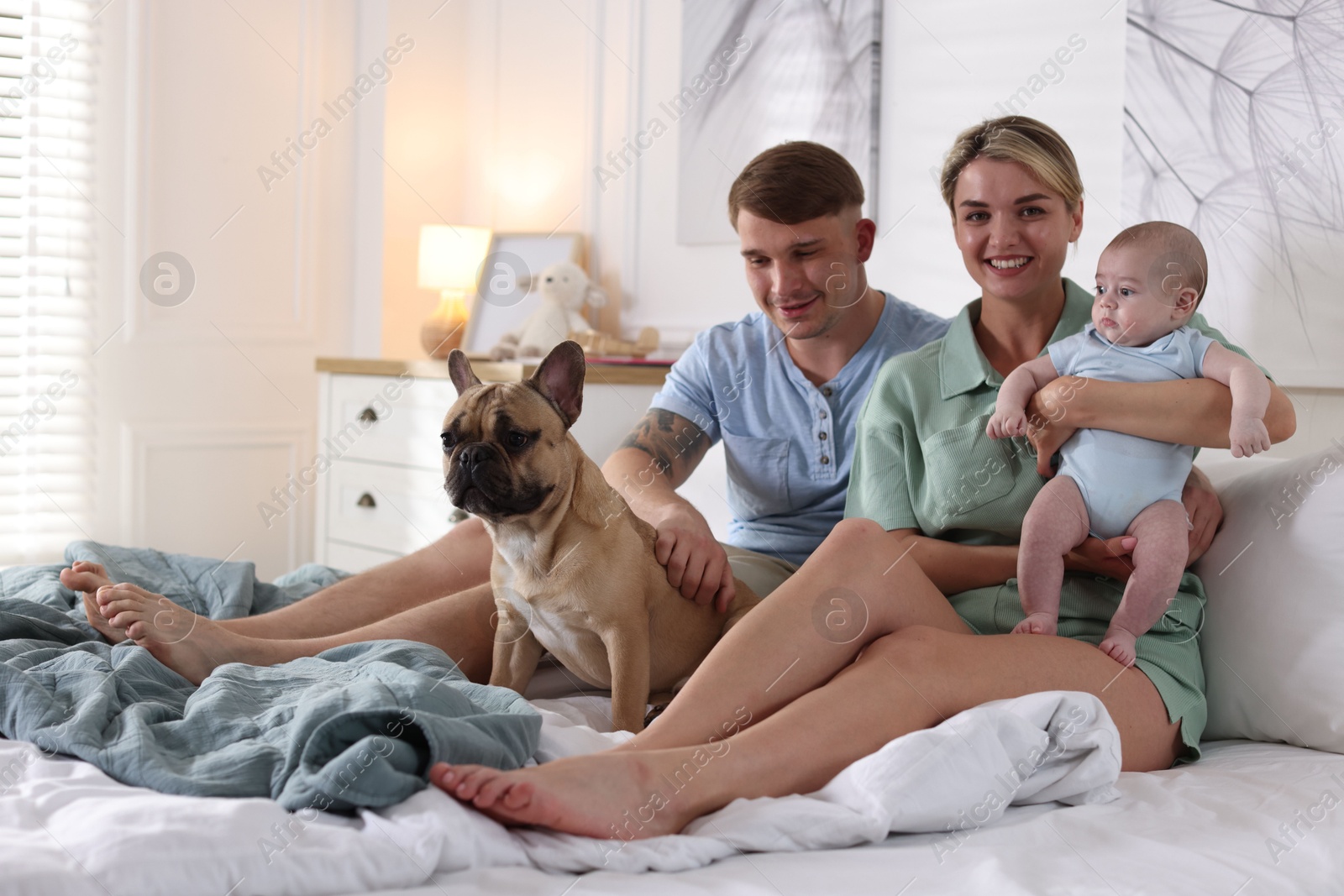 Happy family with little baby and cute dog on bed at home Photo of Happy family with little baby and cute dog on bed at home