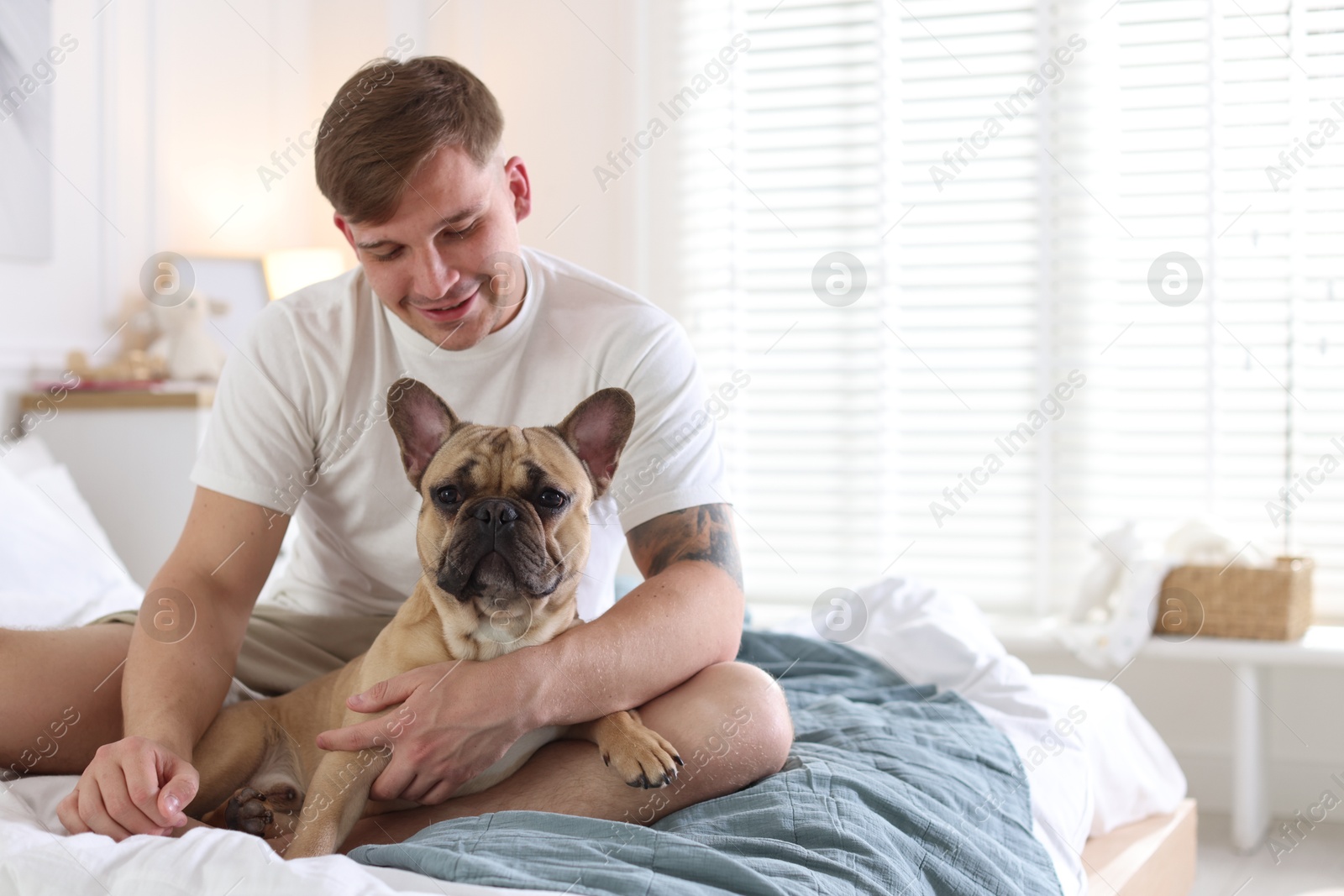 Man with his cute dog on bed at home. Space for text Photo of Man with his cute dog on bed at home. Space for text