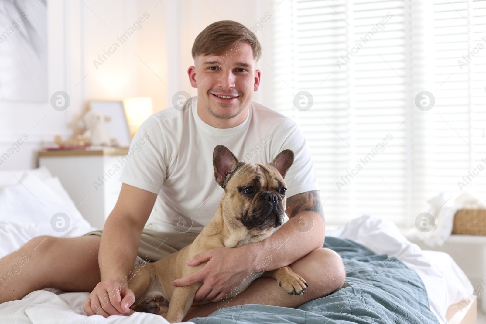 Man with his cute dog on bed at home Photo of Man with his cute dog on bed at home