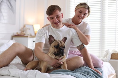 Photo of Happy couple with cute dog on bed at home