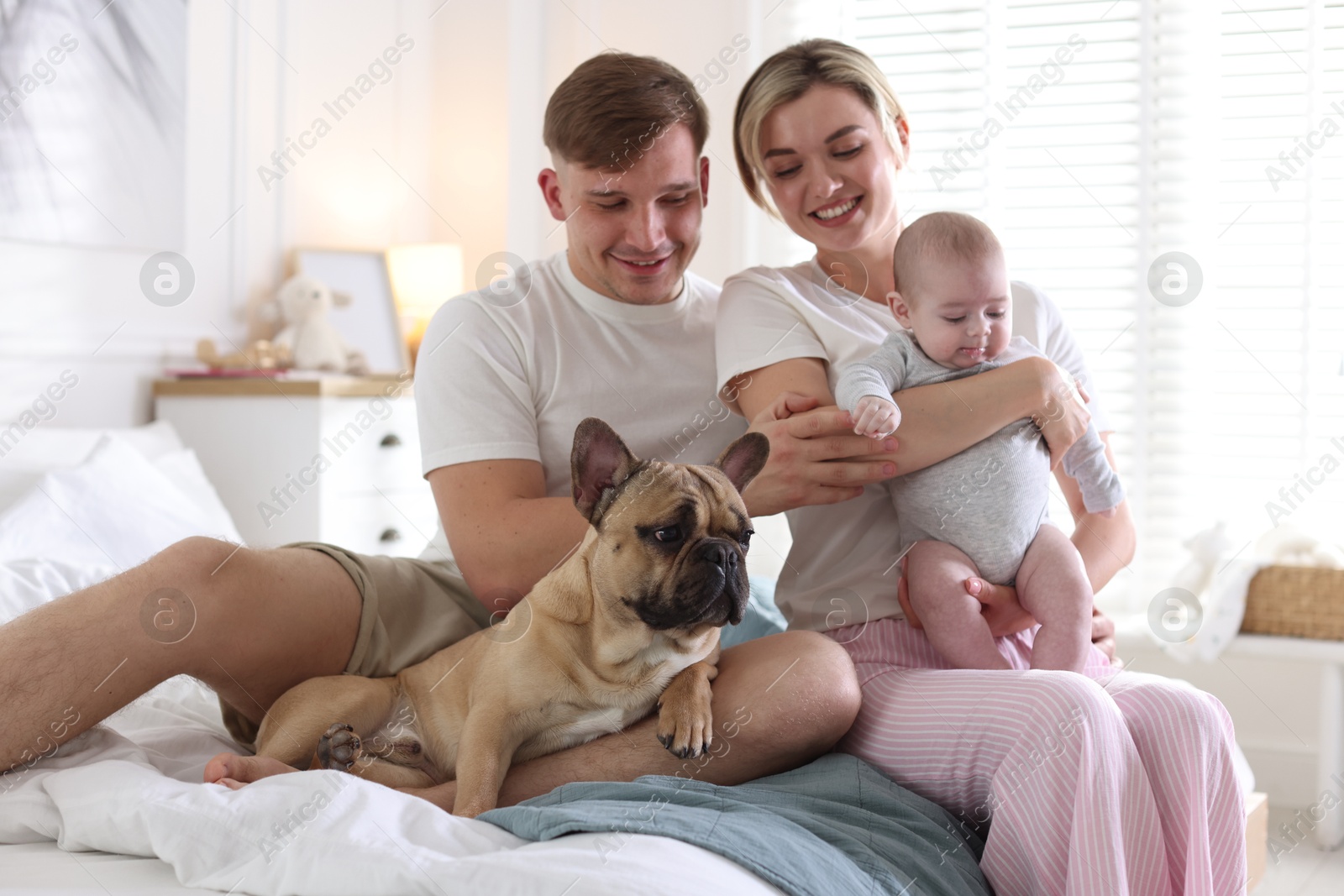 Happy family with little baby and cute dog on bed at home Photo of Happy family with little baby and cute dog on bed at home