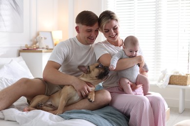 Photo of Happy family with little baby and cute dog on bed at home