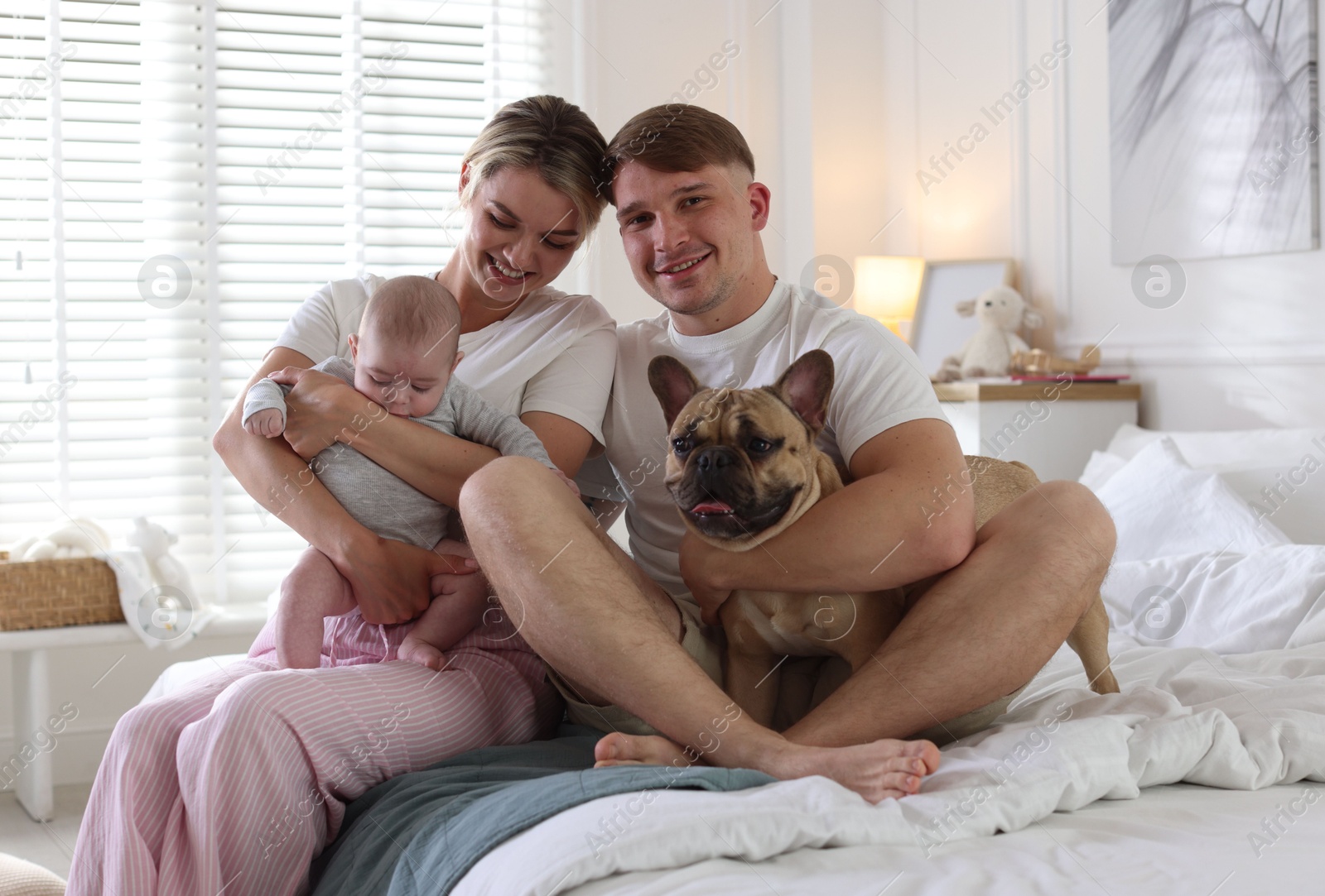 Happy family with little baby and cute dog on bed at home Photo of Happy family with little baby and cute dog on bed at home