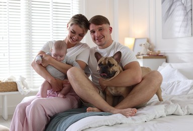 Photo of Happy family with little baby and cute dog on bed at home