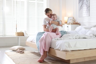 Photo of Mother and her cute baby on bed at home. Space for text
