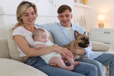 Photo of Happy family with little baby and cute dog on sofa at home