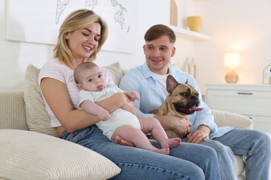 Photo of Happy family with little baby and cute dog on sofa at home