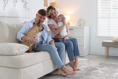 Photo of Happy family with little baby and cute dog on sofa at home. Space for text