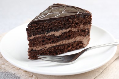 Photo of Piece of delicious chocolate cake and fork on table, closeup