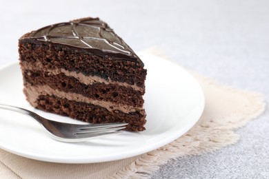 Photo of Piece of delicious chocolate cake and fork on grey table, closeup