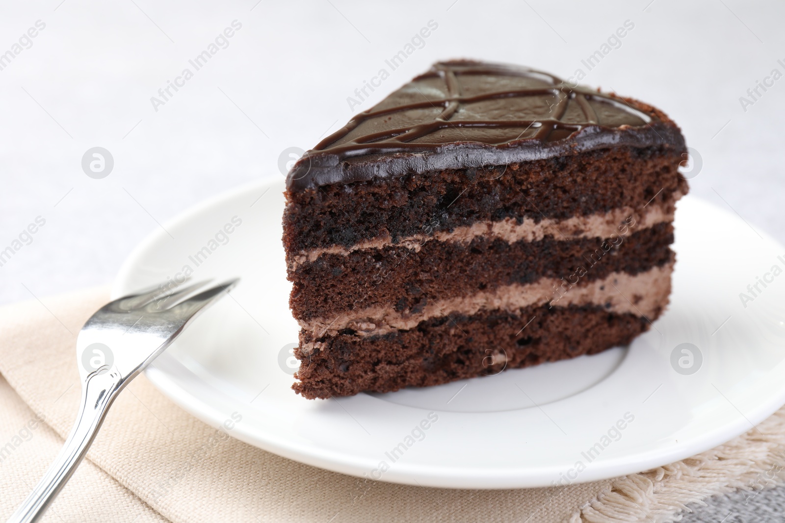Piece of delicious chocolate cake and fork on table, closeup Photo of Piece of delicious chocolate cake and fork on table, closeup