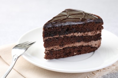 Piece of delicious chocolate cake and fork on table, closeup