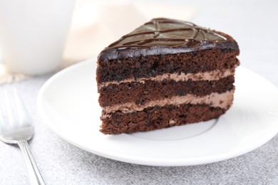 Photo of Piece of delicious chocolate cake and fork on grey table, closeup