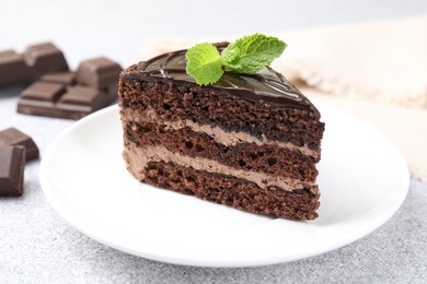 Photo of Piece of delicious chocolate cake with mint on grey table, closeup