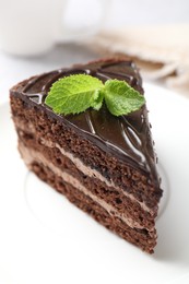 Photo of Piece of delicious chocolate cake with mint on table, closeup