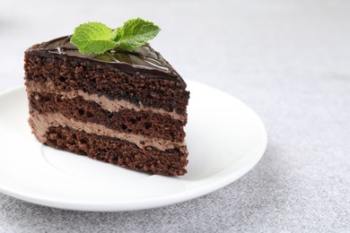 Photo of Piece of delicious chocolate cake with mint on grey table, closeup. Space for text