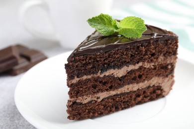 Photo of Piece of delicious chocolate cake with mint on table, closeup