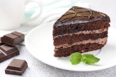 Photo of Piece of delicious chocolate cake with mint on grey table, closeup