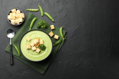 Photo of Tasty pea cream soup with croutons and broccoli served on black table, flat lay. Space for text