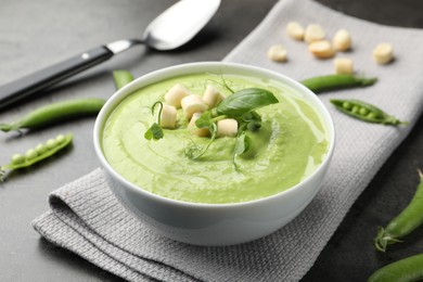 Photo of Tasty pea cream soup with croutons, basil and microgreens served on grey table, closeup