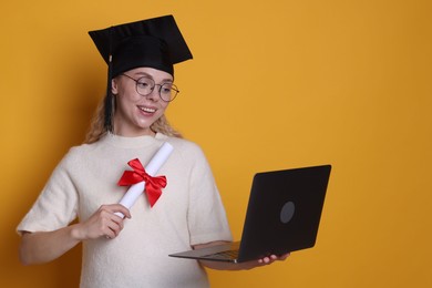Photo of Happy student with diploma and laptop after graduation on orange background