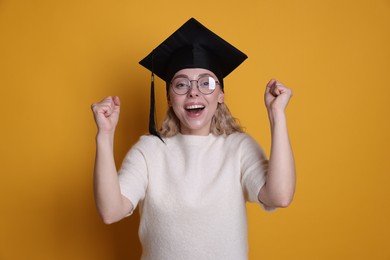 Photo of Happy student after graduation on orange background