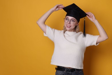 Photo of Happy student after graduation on orange background. Space for text