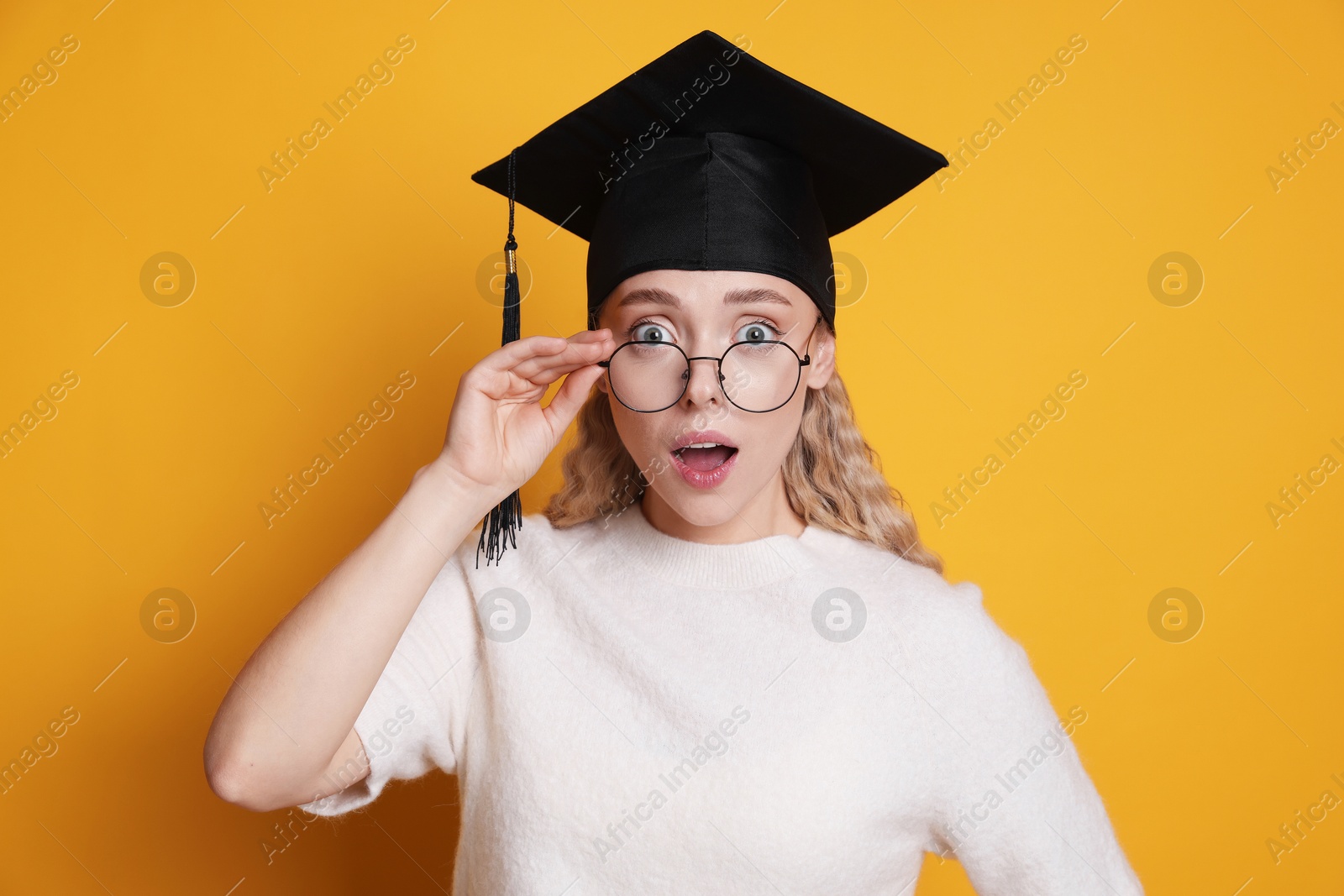Excited student after graduation on orange background Photo of Excited student after graduation on orange background