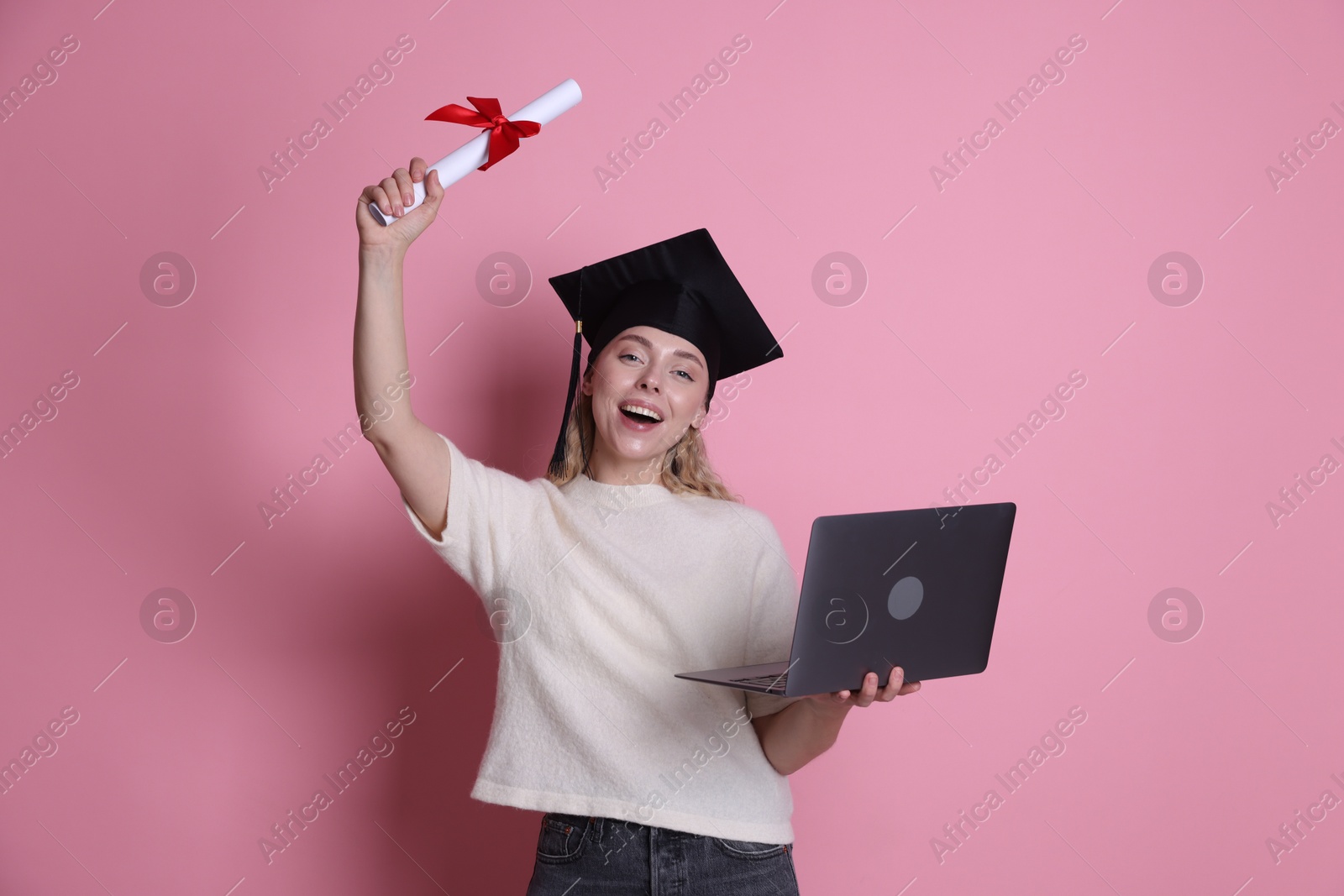 Happy student with diploma and laptop after graduation on pink background Photo of Happy student with diploma and laptop after graduation on pink background