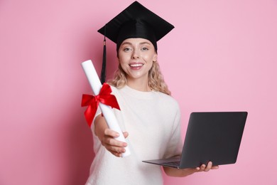 Photo of Happy student with diploma and laptop after graduation on pink background