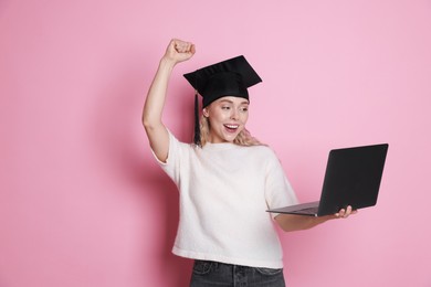Photo of Happy student with laptop after graduation on pink background