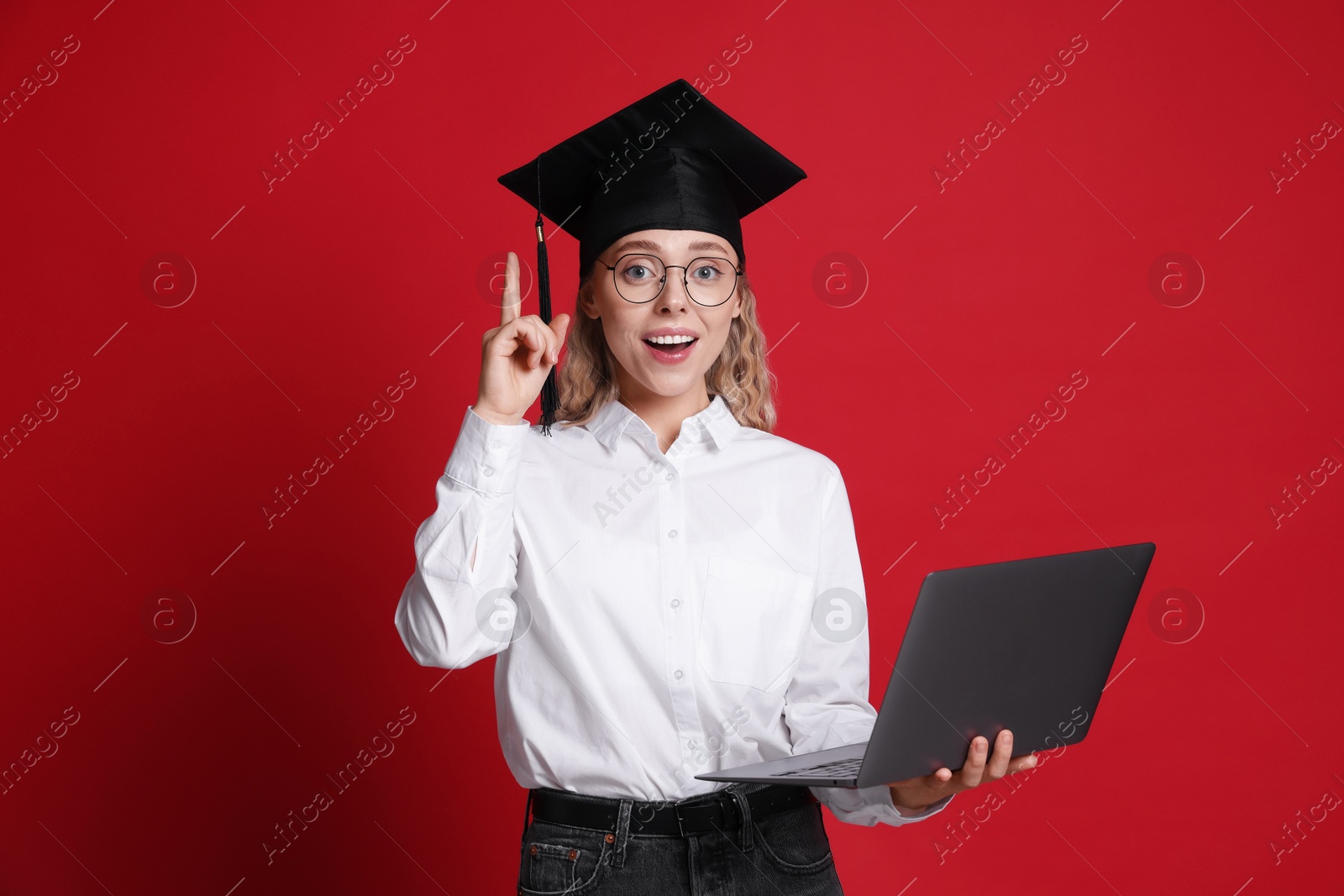 Happy student with laptop after graduation on red background Photo of Happy student with laptop after graduation on red background