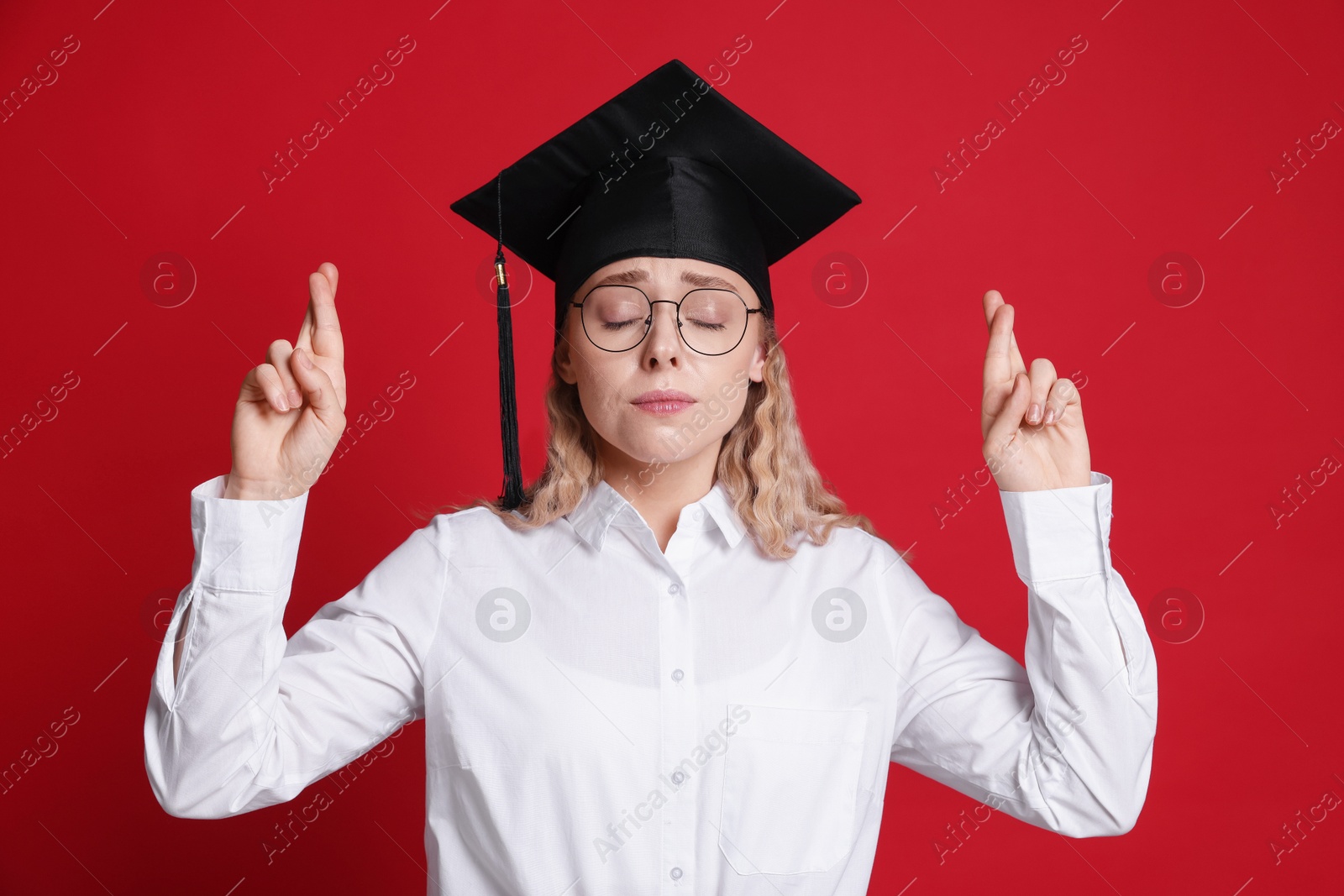Emotional student crossing fingers on red background. Hope for good graduation Photo of Emotional student crossing fingers on red background. Hope for good graduation