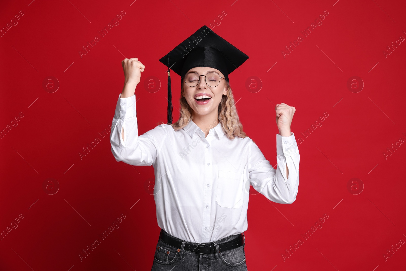 Happy student after graduation on red background Photo of Happy student after graduation on red background