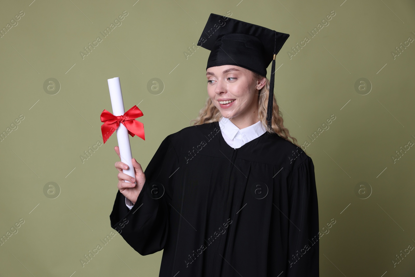 Happy student with diploma after graduation on green background Photo of Happy student with diploma after graduation on green background