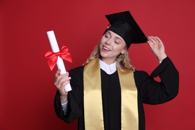 Photo of Happy student with diploma after graduation on red background