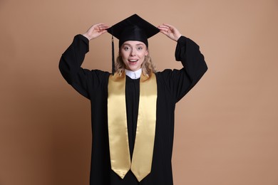 Photo of Happy student after graduation on beige background