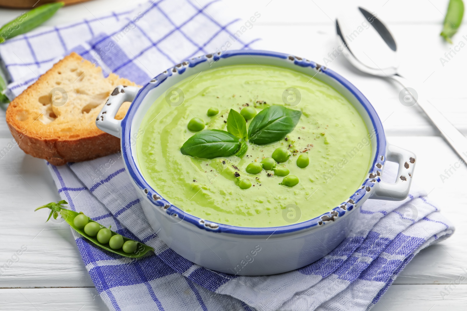 Tasty pea cream soup with basil served on white wooden table, closeup Photo of Tasty pea cream soup with basil served on white wooden table, closeup