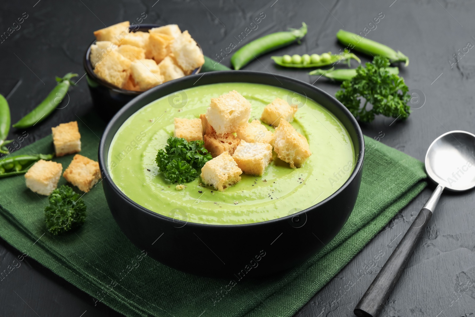 Tasty pea cream soup with croutons and broccoli served on black table, closeup Photo of Tasty pea cream soup with croutons and broccoli served on black table, closeup