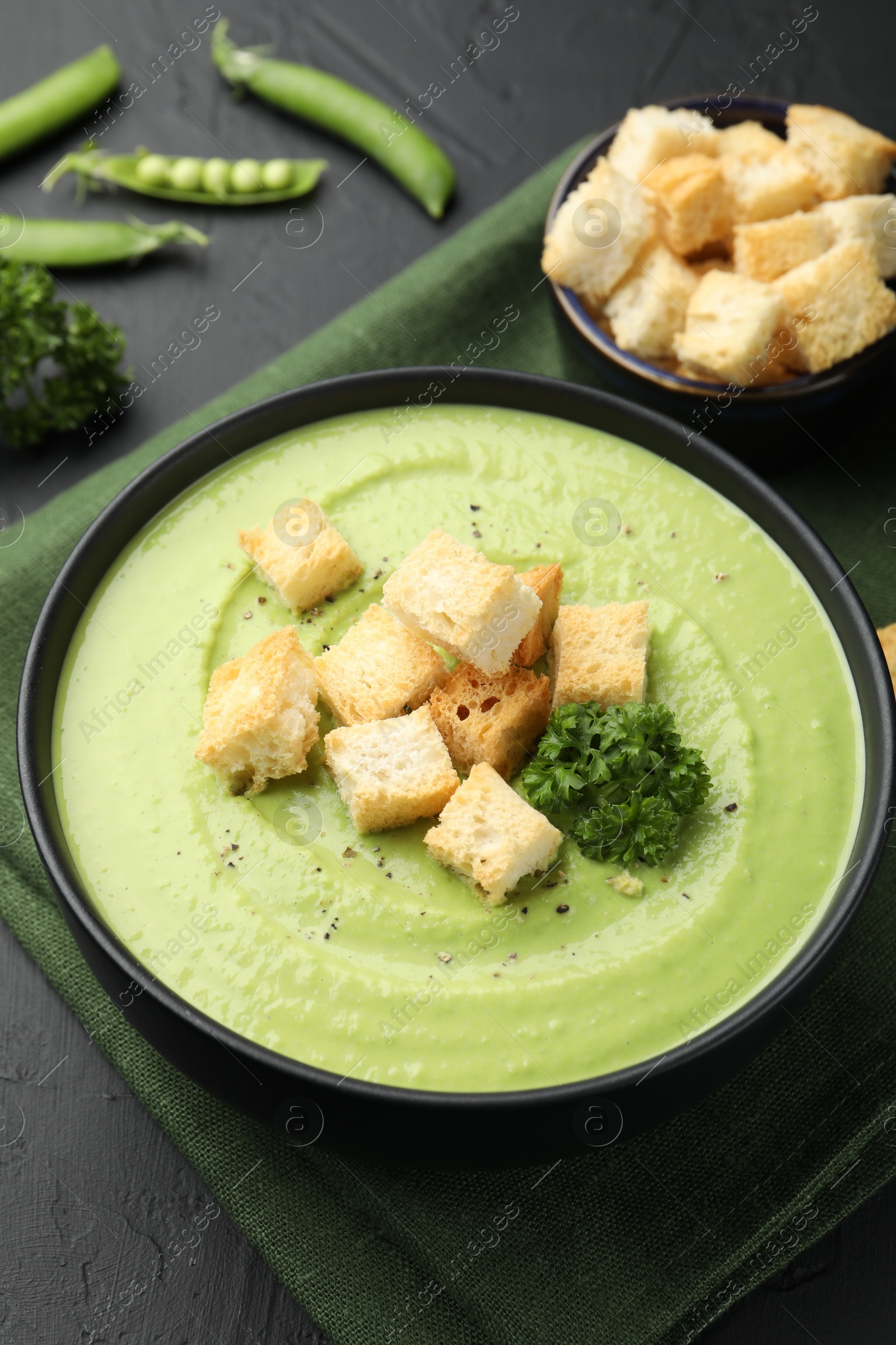 Tasty pea cream soup with croutons and broccoli served on black table, closeup Photo of Tasty pea cream soup with croutons and broccoli served on black table, closeup