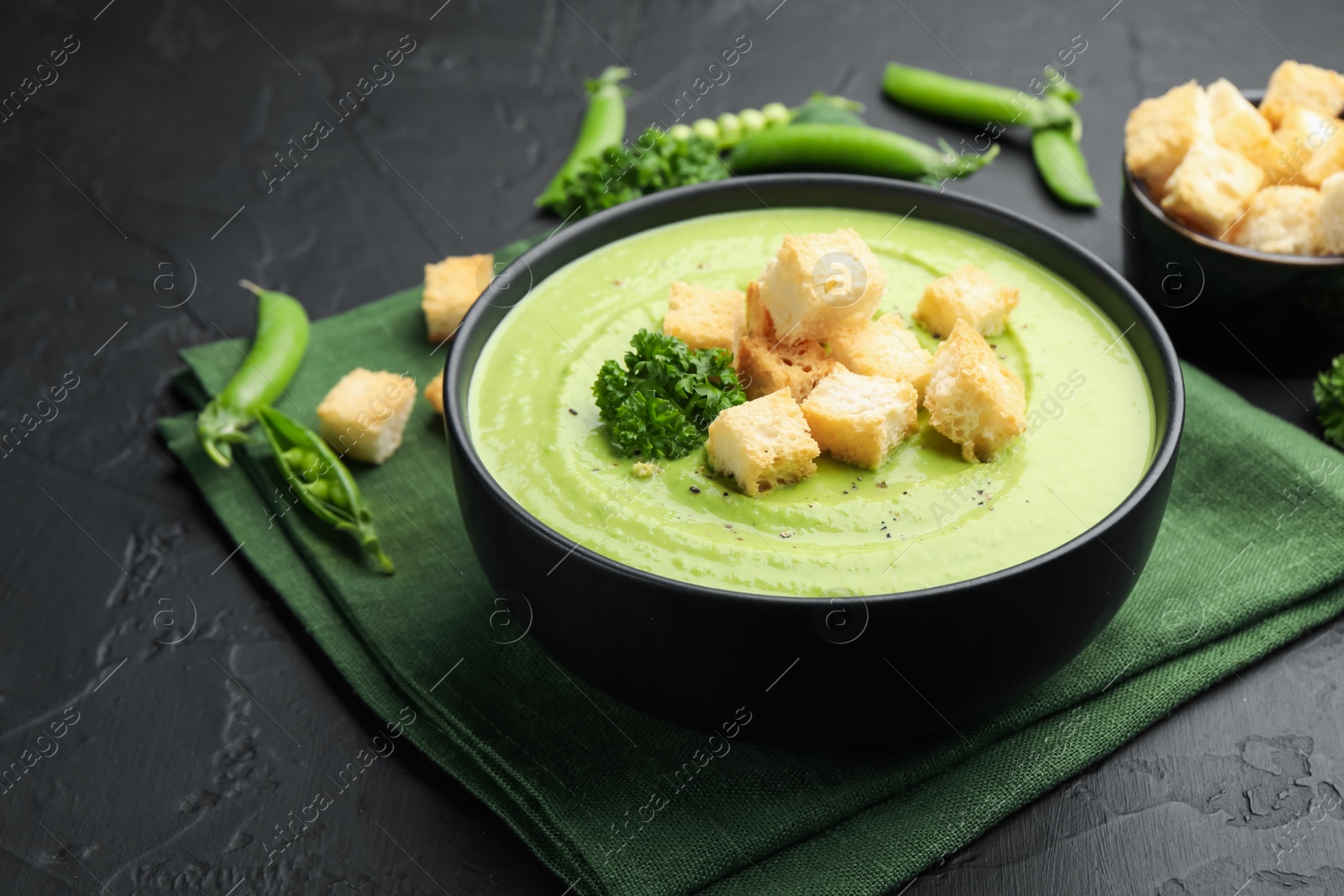 Tasty pea cream soup with croutons and broccoli served on black table, closeup Photo of Tasty pea cream soup with croutons and broccoli served on black table, closeup