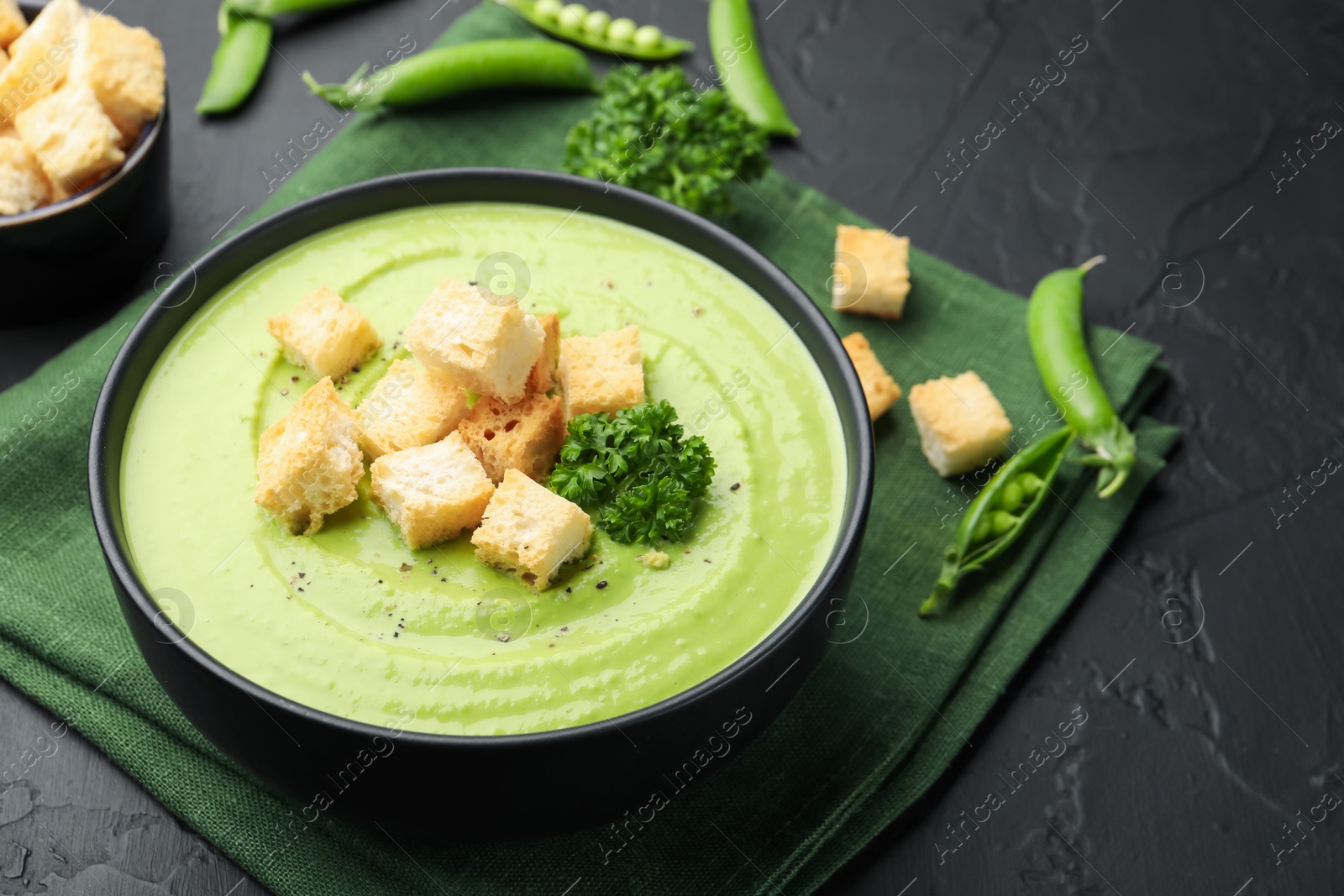 Tasty pea cream soup with croutons and broccoli served on black table, closeup Photo of Tasty pea cream soup with croutons and broccoli served on black table, closeup