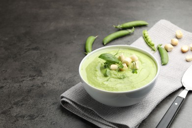 Photo of Tasty pea cream soup with croutons, basil and microgreens served on grey table. Space for text