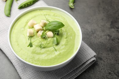 Photo of Tasty pea cream soup with croutons, basil and microgreens served on grey table, closeup