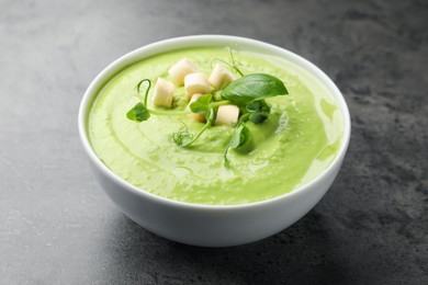 Photo of Tasty pea cream soup with croutons, basil and microgreens
