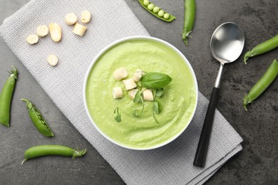 Photo of Tasty pea cream soup with croutons, basil and microgreens served on grey table, flat lay